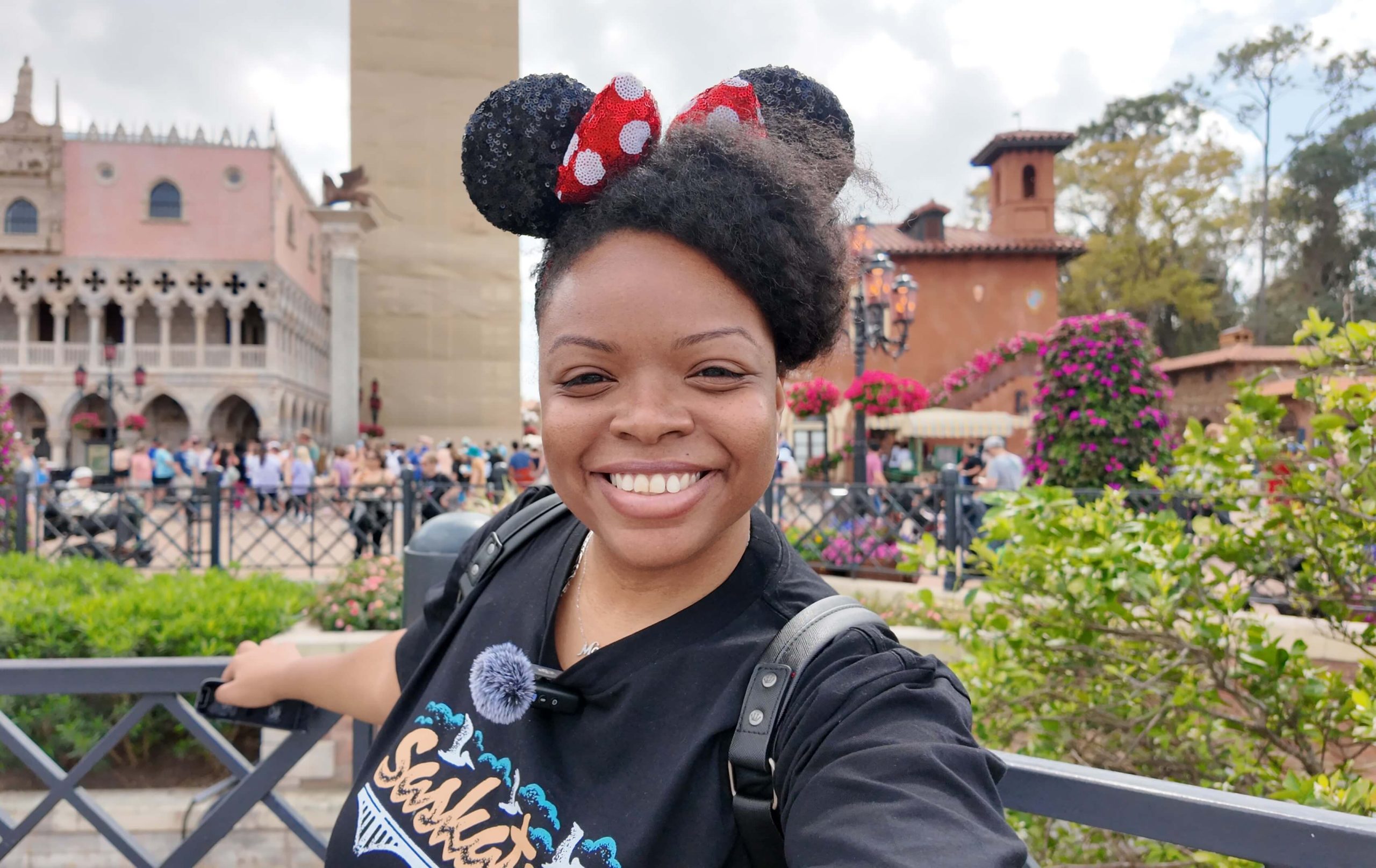 Disney Moms Planning Guide. Smiling woman wearing red sequined Minnie ears takes a selfie while walking through the lush Pandora The World of Avatar area at Disney's Animal Kingdom with two companions behind her. This vacation moment highlights the adventure and fun Disney Moms can enjoy while exploring immersive themed lands together.