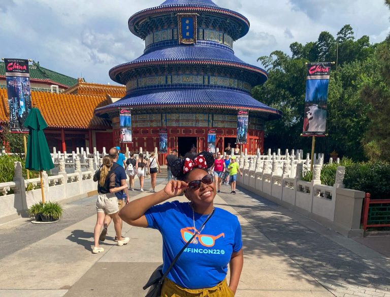 A woman poses in front of the China Pavilion at EPCOT in Walt Disney World, with the pavilion's traditional Chinese architecture visible behind her. This is just one of the experiences you can expect when you create a budget for Disney World.