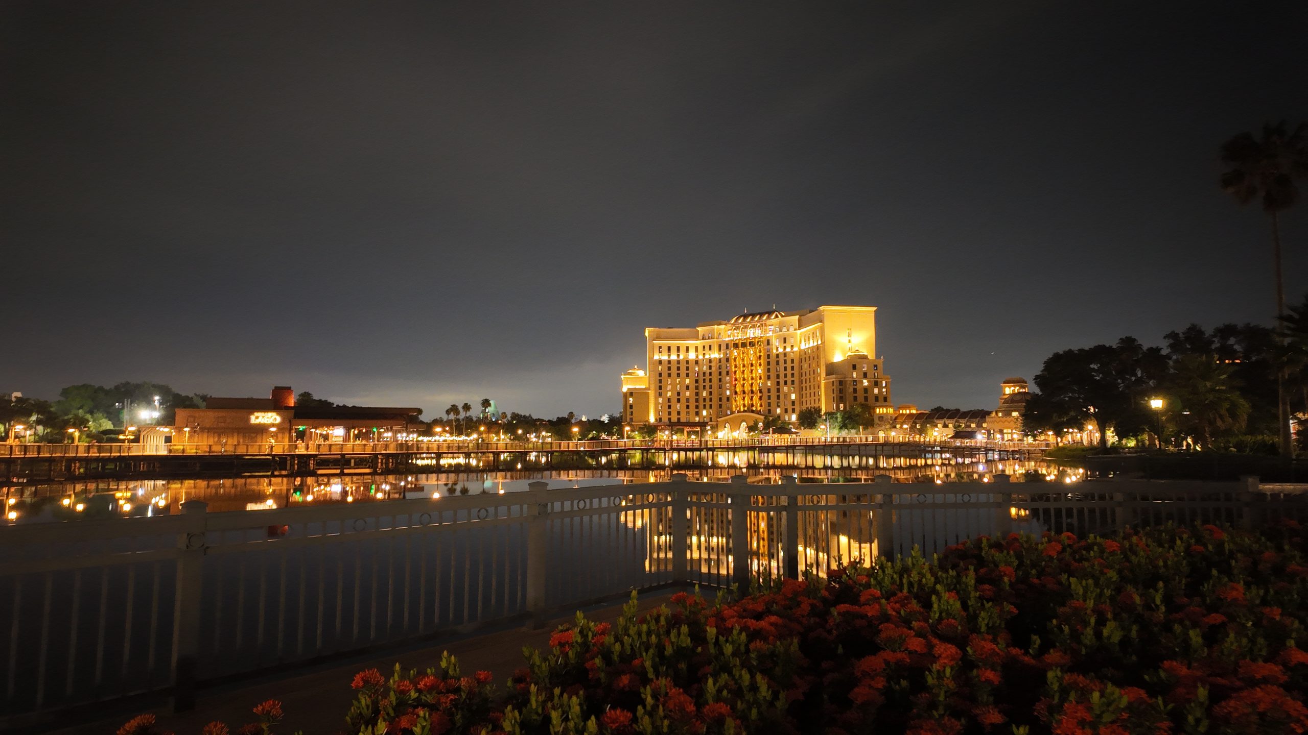 The brightly lit Gran Destino Tower at Disney’s Coronado Springs Resort reflects across Lago Dorado at night. This nighttime view highlights the resort setting featured in a Disney Coronado Springs review.